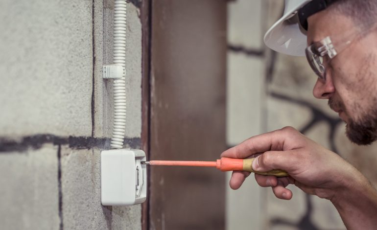 male electrician technician connects equipment with tool